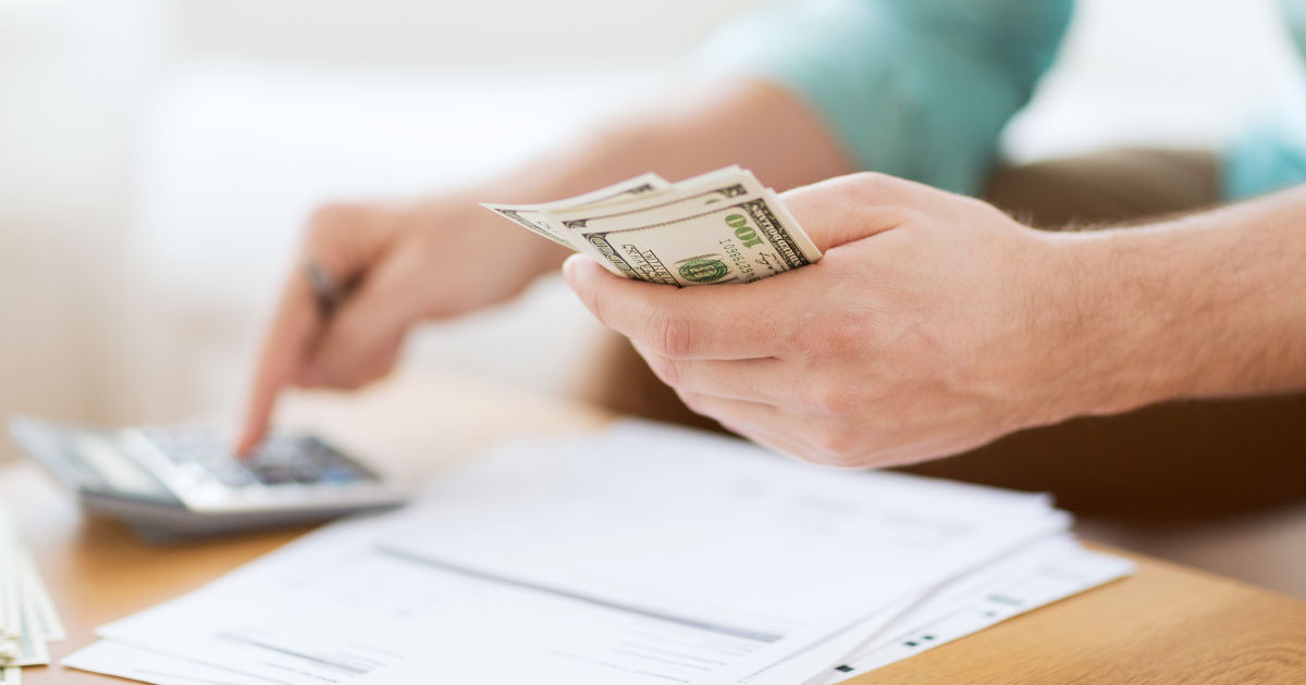 man with calculator counting money making notes
